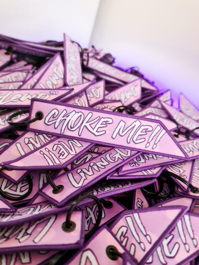 Flight tag  in a pink and purple colour scheme featuring the words "choke me" 